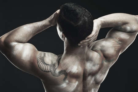 Strong body, strong mind. Monochrome shot of a muscular young man posing nude in studio against a dark background.の写真素材