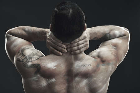 Built like a god. Monochrome shot of a muscular young man posing nude in studio against a dark...