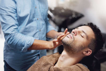 Hes ready to be pampered. a handsome young man getting groomed by a barber.の写真素材