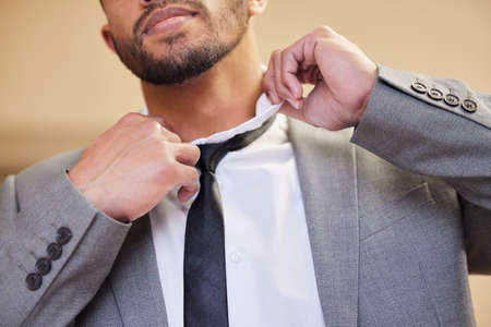 Looking for the right tie to complete the look. Low angle shot of an unrecognizable young man putting on a tie in his bedroom at home.の写真素材