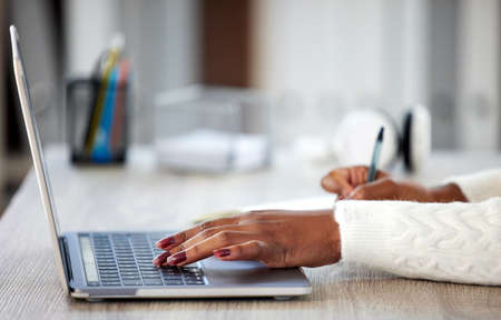 Home is the place for productivity. an unrecognisable woman making notes in a book while studying at...