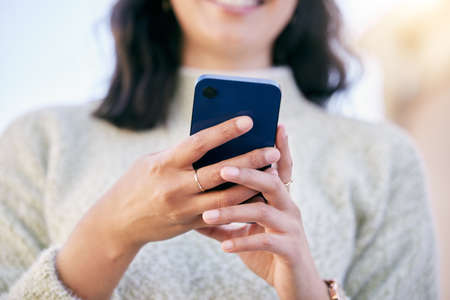 Its almost done downloading. a woman using her cellphone while standing outside.の写真素材