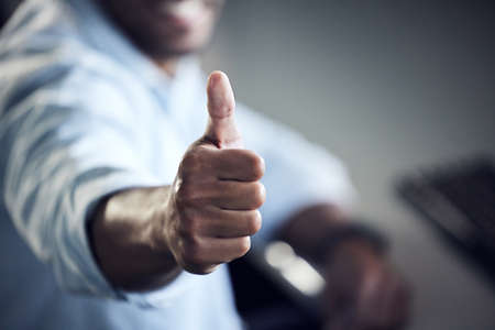 I got my degree in IT. an unrecognisable man showing thumbs up and using a computer at college.