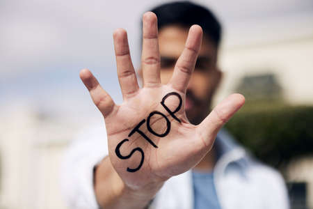 Stop waiting for change and make it yourself. a young man showing his hand with the word stop...