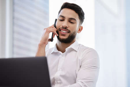 Update me about your progress. a young businessman making a call using his smartphone.