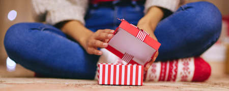 A little gift that means a lot. a unrecognisable woman opening presents during Christmas at home.