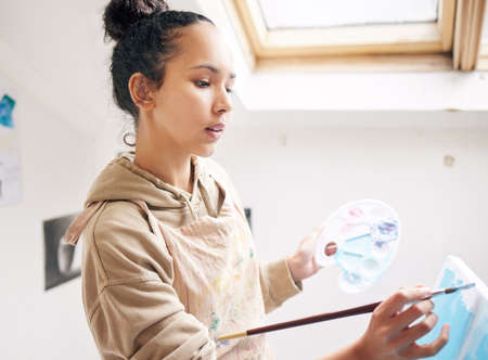 Letting her imagination speak. High angle shot of an attractive young woman painting on a canvas in...