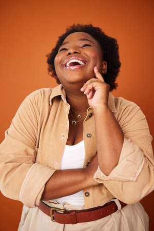 Laughter makes it all better. a young woman posing against an orange background.の写真素材