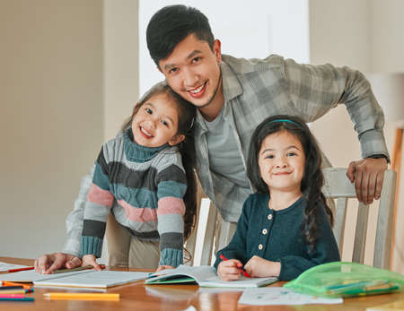 Im always a proud dad. a young father helping his daughters with their homework.の写真素材