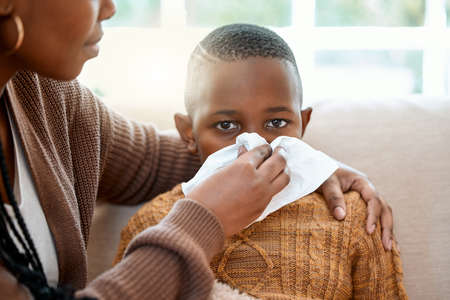 Shell nurse you back to health. a young mother helping her son blow his nose at home.の写真素材
