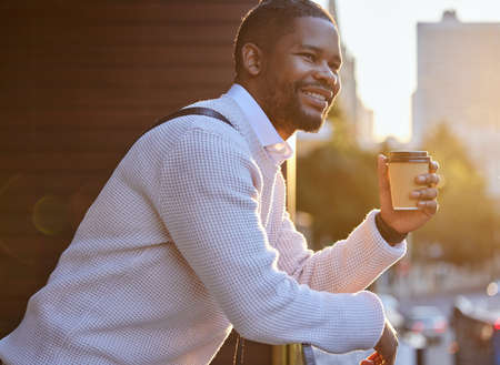 Be appreciative, optimistic and positive about life. a young businessman drinking coffee while standing on the balcony of an office.の写真素材