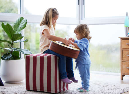 Youre not too young to learn. two little sisters playing the guitar at home.の写真素材