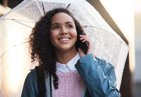 Ill be there soon. a young woman on a call while holding an umbrella in the city.