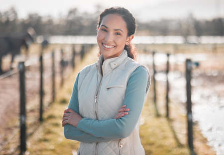 There are always things to do around here. an attractive young woman standing alone on her farm with her arms folded.の写真素材