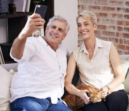 Snapping some family portraits. a mature couple taking selfies while relaxing with their pet cat on...