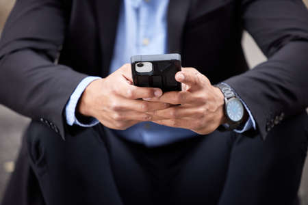 I should probably book a ride. an unrecognizable businessman sitting and using his cellphone in the...