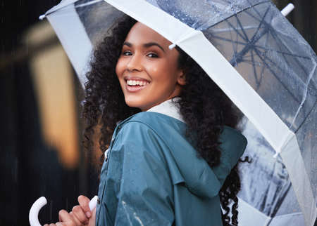 This really is my kind of weather. a young woman holding an umbrella in the city.の写真素材