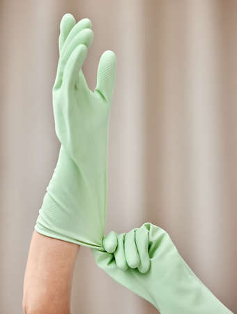 Have to protect my hands. an unrecognizable person putting on gloves at home.の写真素材