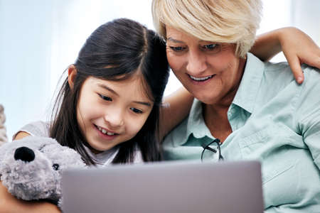 This app has something for everyone. a little girl and her grandmother looking at something on a digital tablet.の写真素材