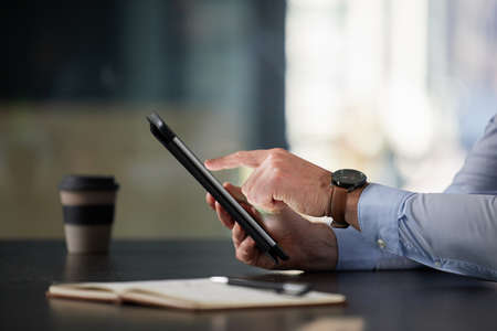 Getting multiple tasks done in an instant. Closeup shot of an unrecognisable businessman using a digital tablet in an office.の写真素材