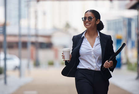 Another day of working towards success. an attractive young businesswoman walking through the city during her morning commute.の写真素材
