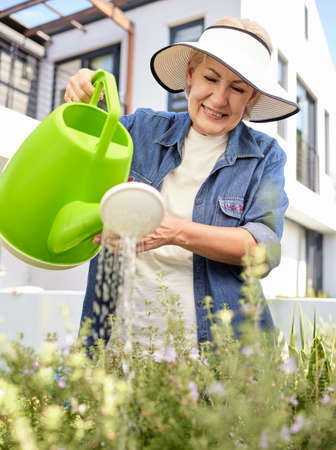 Plants need a little love too. a senior woman gardening in the backyard at home.の写真素材