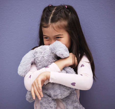 We share a special bond. an adorable little girl holding on to her stuffed animal.の写真素材