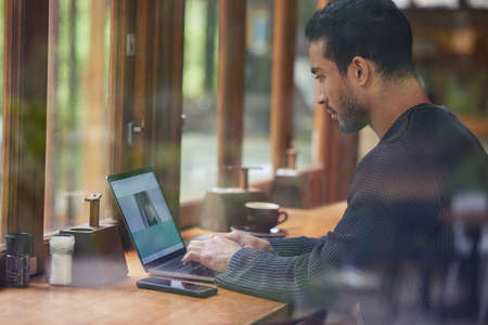 Bringing my work to my local cafe sure was a good idea. a man using his laptop while sitting in a...