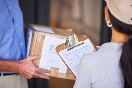 Your package has arrived. High angle shot of an unrecognizable man taking delivery of a package from...