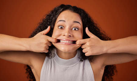 Smile. Cropped portrait of an attractive young woman making a face in studio against a red...