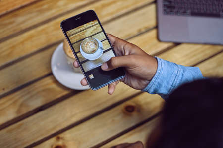 Coffee lovers cant not take pictures of perfect coffee. an unrecognizable man sitting in a cafe and...