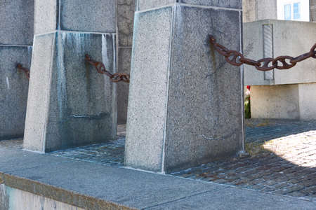 Closeup of concrete structures on the promenade by a harbour with copy space. Rusty chains hanging...