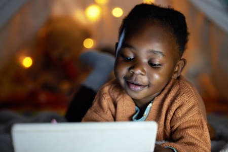 Fun stories make bedtime even better. an adorable little girl using a digital tablet during bedtime...