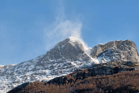 Beautiful landscape of a snowy mountain top with a blue sky and copy space. A streaming peak with...