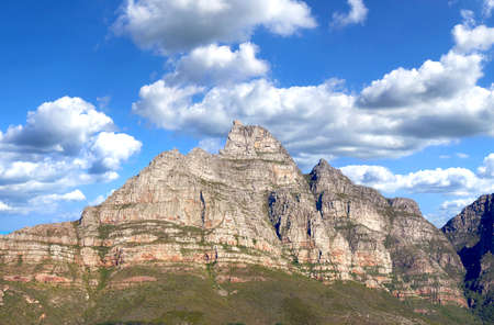 Landscape of mountains on a blue cloudy sky. Beautiful view of mountain outcrops with hill covered...