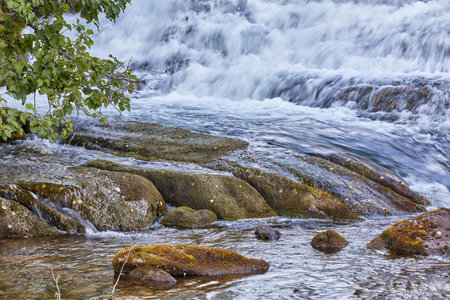 Mountain stream and waterfall rushing down over rocks and boulders. Beautiful nature landscape...