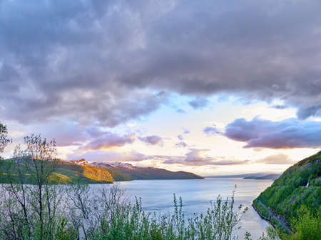 Scenic view of a lake, ocean or sea with cloudy sky at sunset and copy space.Uncultivated trees,...