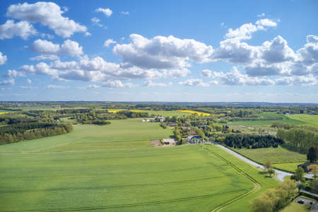 Drone view of farming and agricultural fields outdoors in Europe during summer or spring. Vibrant and bright pastures growing on endless farmland with blue sky background over a vast and open meadowの写真素材