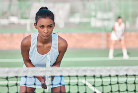 A pro knows all about staying fully focused. a sporty young woman playing tennis on a court.の写真素材