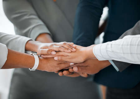 Lets go team. a group of unrecognizable businesspeople standing in the office with their hands in a...