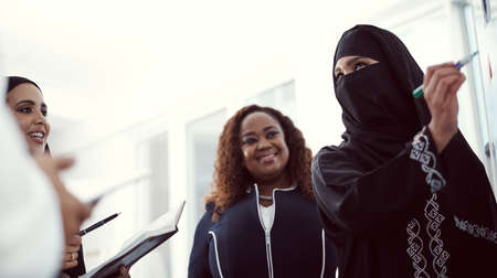Low angle shot of a group of diverse business colleagues working together on a whiteboard in their office.の写真素材