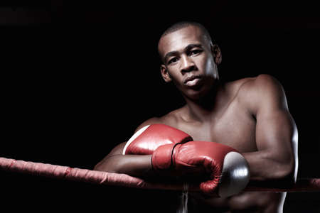 Strong well built boxer. Portrait of strong well built boxer poses with gloves.