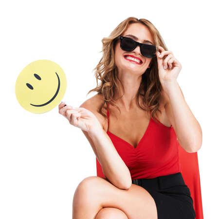 Betting on happiness. A charismatic young woman wearing glasses and holding a paddle with a smiley face on it.の写真素材