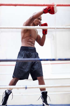 Athletic man practicing. African American athletic man practicing in ring.の写真素材