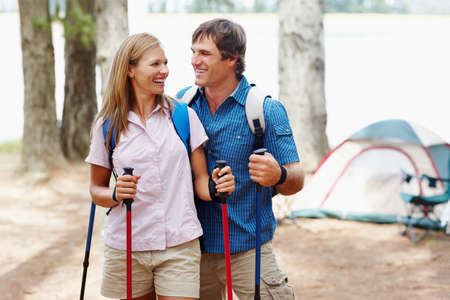 Couple ready for trekking. Happy couple with backpack holding trekking pole and looking at each other.の写真素材