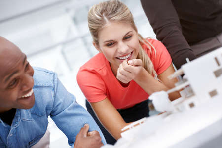 Cheerful moment at the office. A team of architects having a light-hearted moment while standing by...