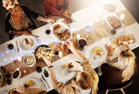 Food is the ingredient that binds us together. High angle shot of friends getting together for a dinner party.の写真素材