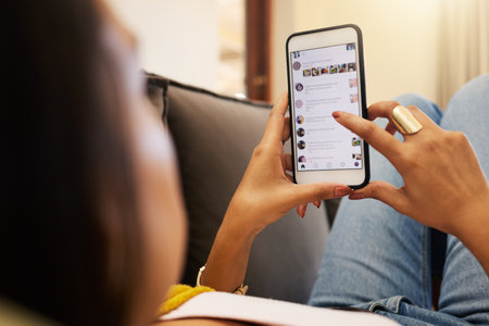 Closeup of woman on her smartphone lying on a sofa, relaxing in a bright living room. A young...