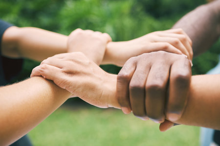Hands holding wrists outside in nature. A diverse group of people holding wrist as a concept of...