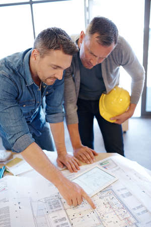 Plans in progress. two architects working together on a blueprint with the help of a digital tablet.